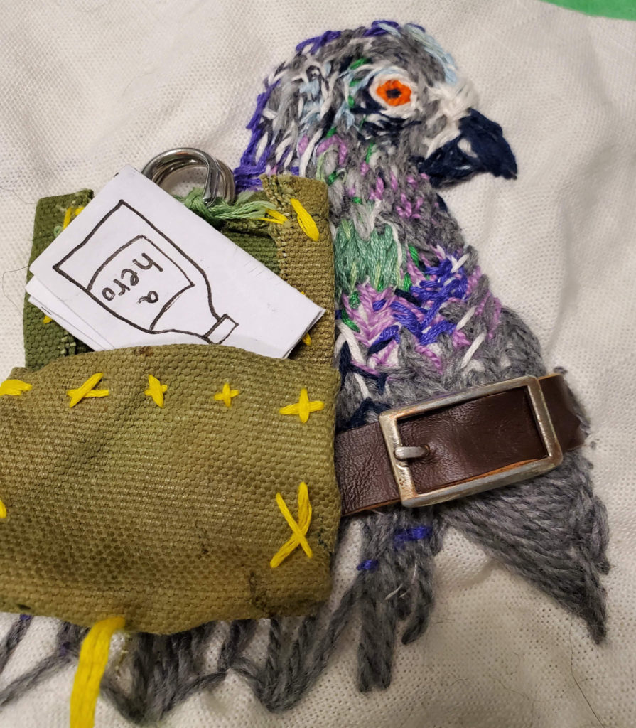 mini zine going into an embroidered pigeon's back pack